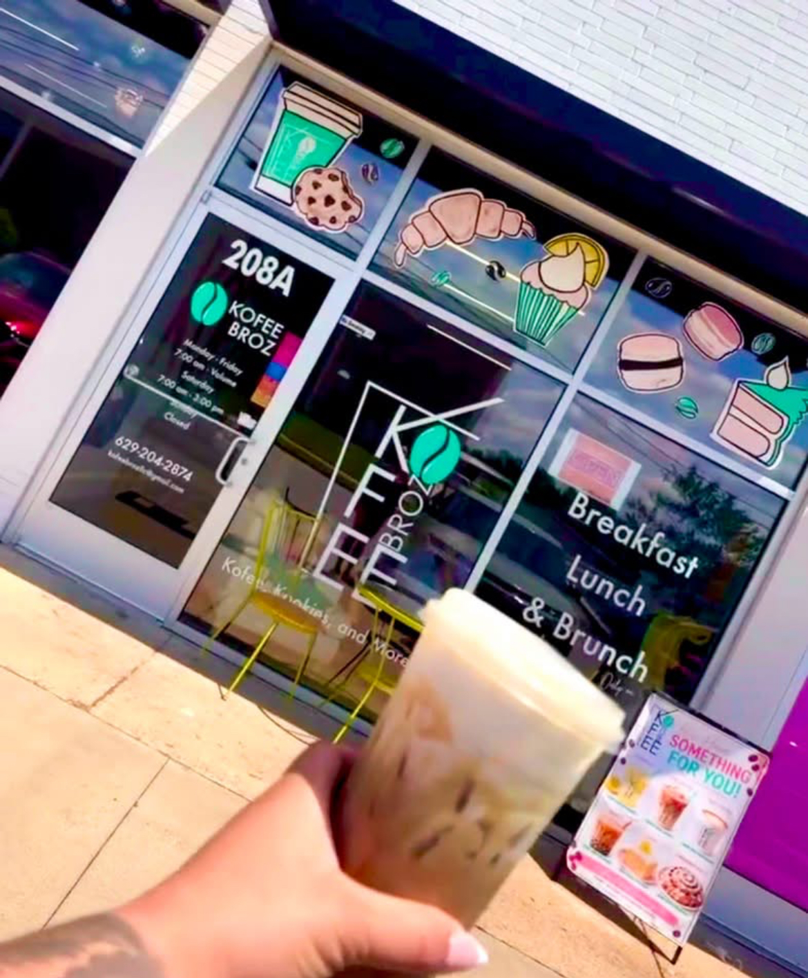 Kofee Broz storefront at 208A with an iced coffee in hand